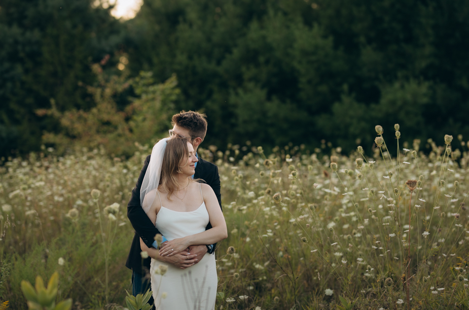 A couple embraces in a field of wildflowers.